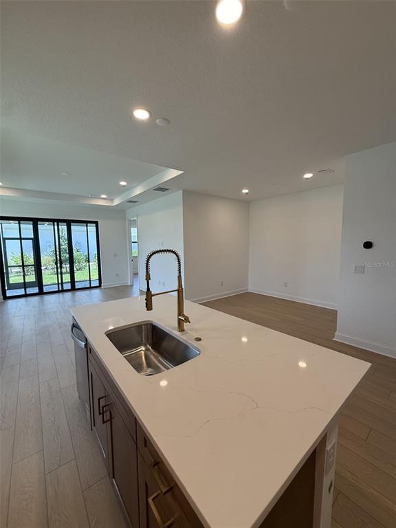 A kitchen island with a gold faucet and white quartz countertop sits in an open-concept room — 5889 WINDBREAK COURT, APOLLO BEACH, FL
