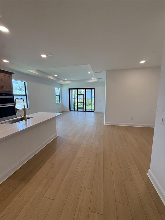 A kitchen with a white island and light wood-look flooring opens to a living area — 5889 WINDBREAK COURT, APOLLO BEACH, FL