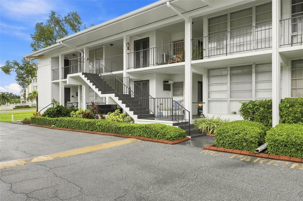 An aerial view shows a multi-story apartment complex near a bridge, marina, and coastal waterway — 2950 W BAY DRIVE UNIT B1, BELLEAIR BLUFFS, FL