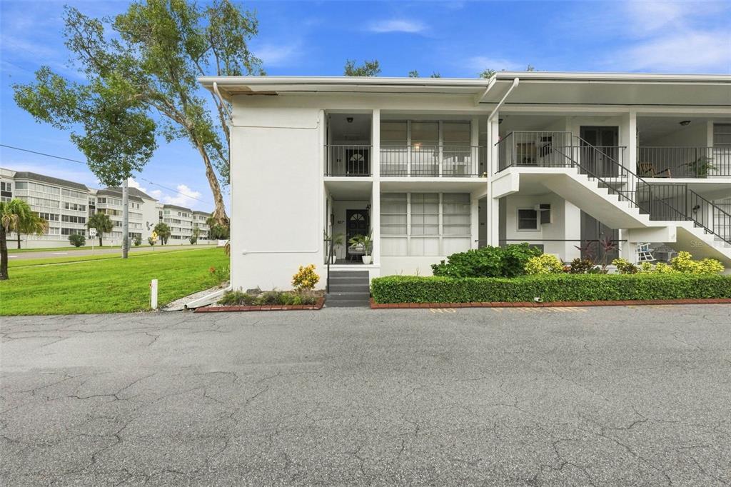 A two-story white apartment building features an exterior staircase and a paved parking lot — 2950 W BAY DRIVE UNIT B1, BELLEAIR BLUFFS, FL