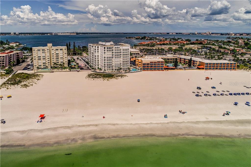 An aerial view of a sandy beach with several multi-story buildings and the ocean — 4950 GULF BOULEVARD UNIT 304, ST PETE BEACH, FL