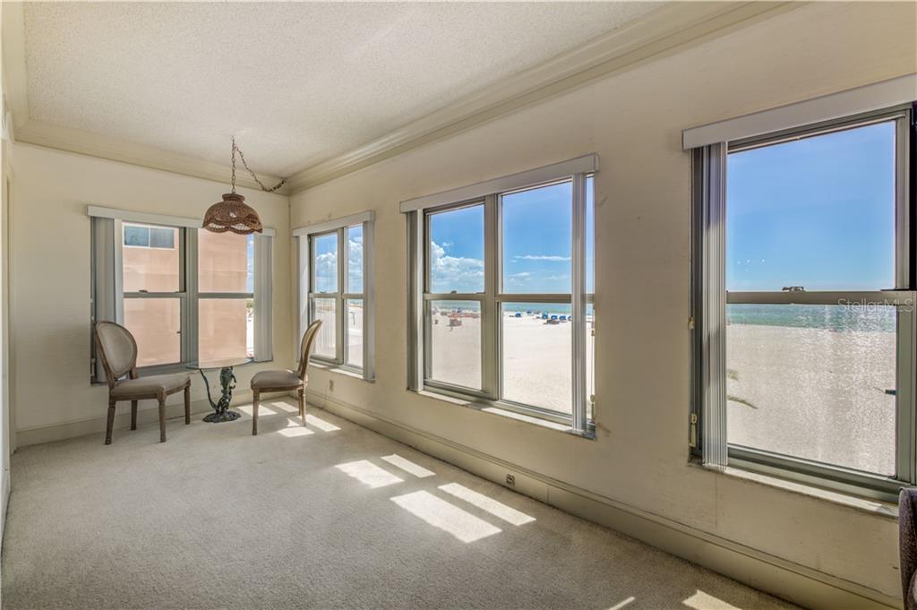 A sunroom with carpeted floors and large windows offering a direct view of the beach — 4950 GULF BOULEVARD UNIT 304, ST PETE BEACH, FL