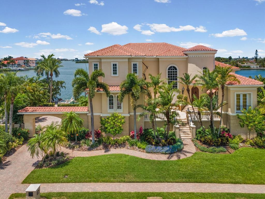 A large, multi-story Mediterranean-style house with a tile roof sits beside a waterfront canal — 6224 PASADENA POINT BOULEVARD, GULFPORT, FL