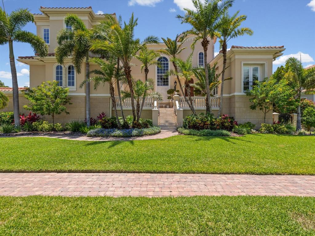 A two-story stucco house with a raised stone terrace, palm trees, and a front lawn — 6224 PASADENA POINT BOULEVARD, GULFPORT, FL