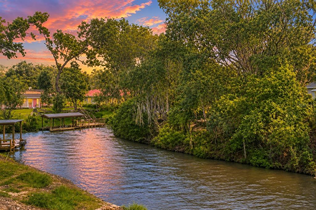 A canal flows past boat docks and lush trees under a vibrant sunset sky — 18 WESTON ROAD, LEESBURG, FL