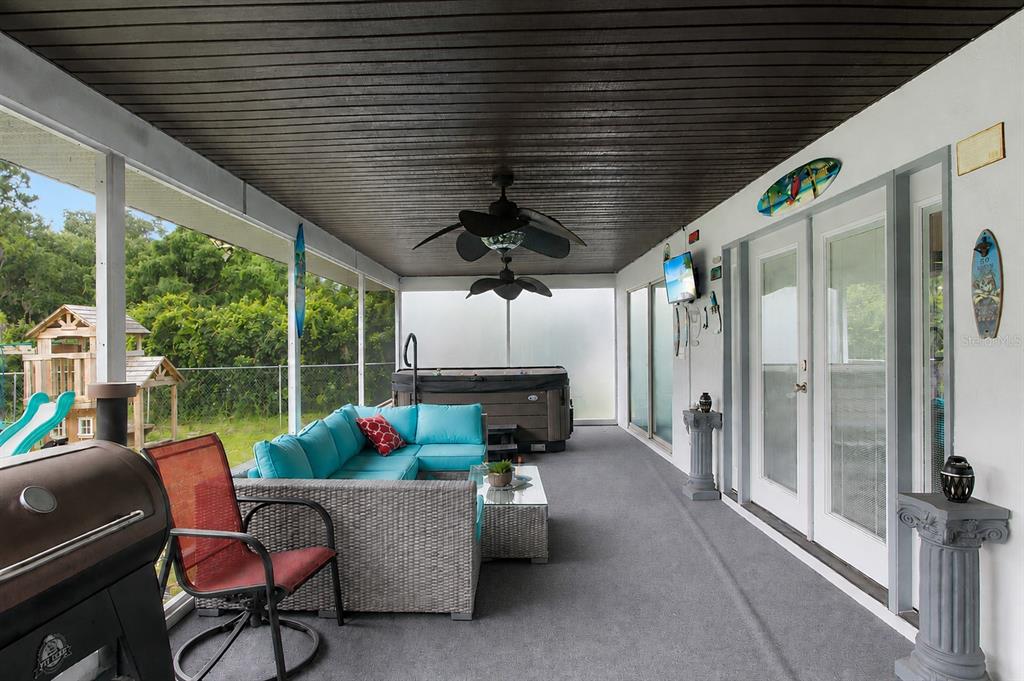 A covered patio features a gray sectional sofa, a hot tub, and a grill — 18 WESTON ROAD, LEESBURG, FL