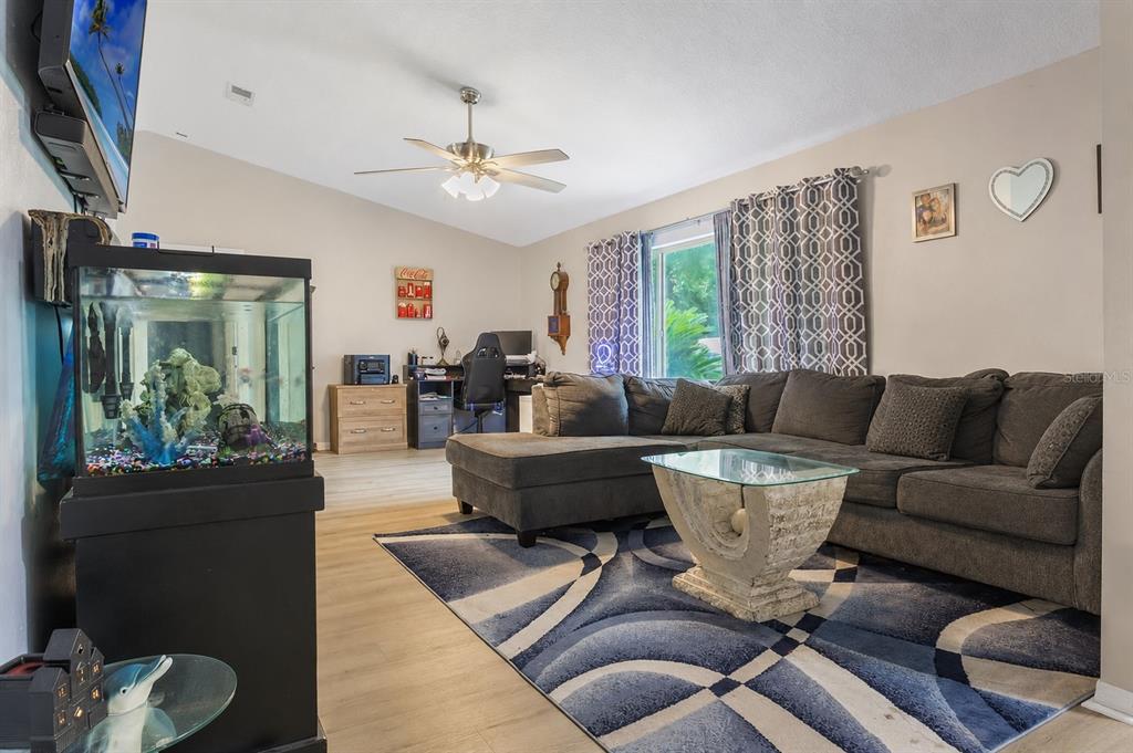 A living room features a gray sectional sofa, a patterned area rug, and a fish tank — 18 WESTON ROAD, LEESBURG, FL