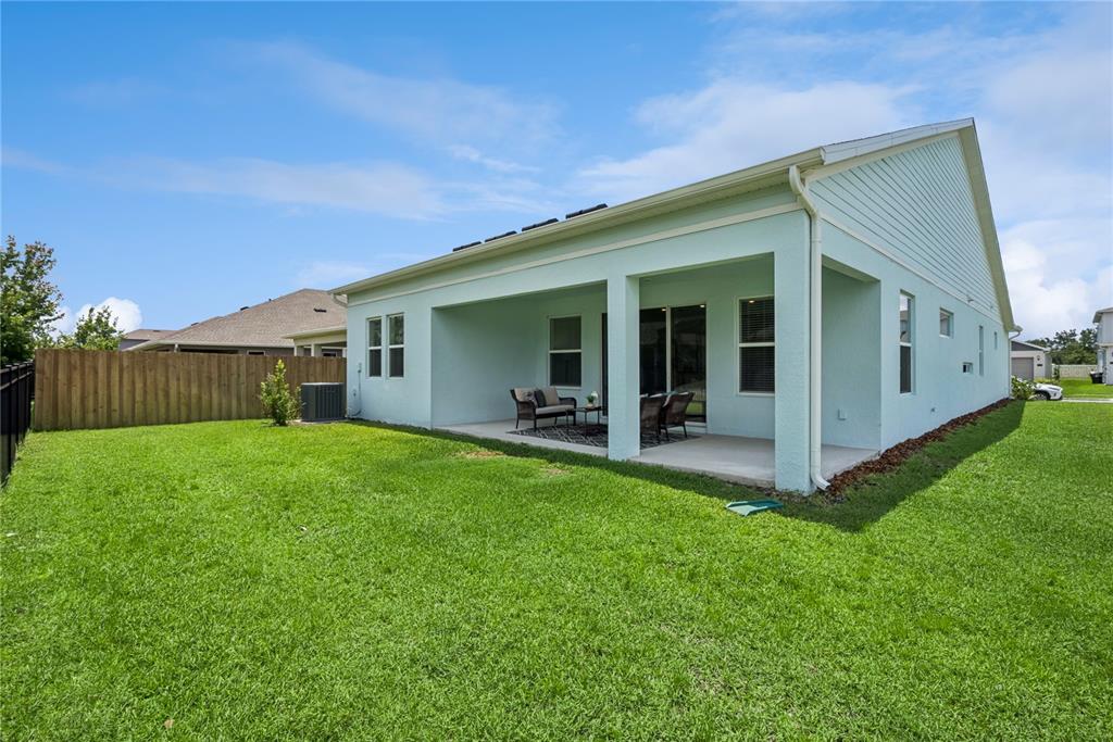 Two adjacent suburban houses with light-colored siding, paved driveways, and manicured lawns under a blue sky — 19307 BANFIELD PLACE, ORLANDO, FL