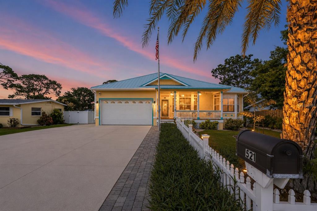 A covered front porch features a stained-glass door, wicker furniture, and a hanging porch swing — 521 S PENINSULA AVENUE, NEW SMYRNA BEACH, FL