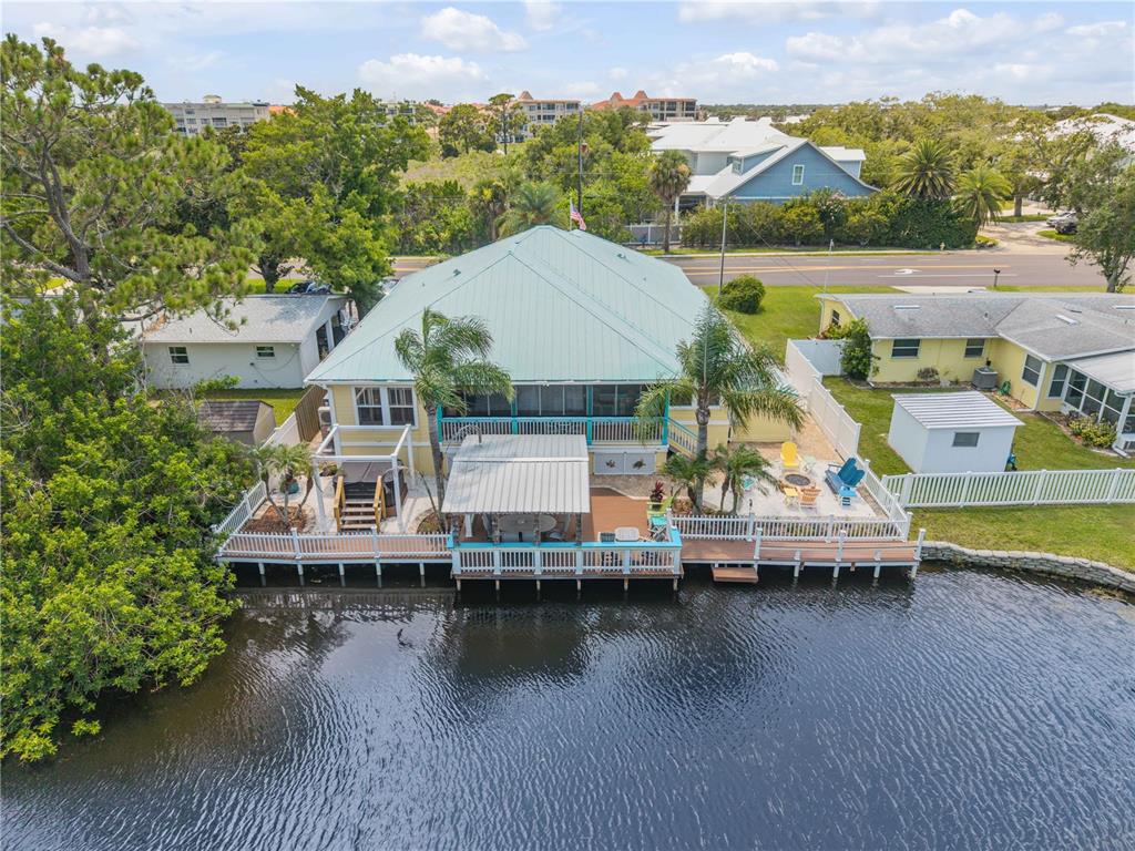 A covered porch features a hanging swing, ceiling fan, and views of a grassy yard — 521 S PENINSULA AVENUE, NEW SMYRNA BEACH, FL
