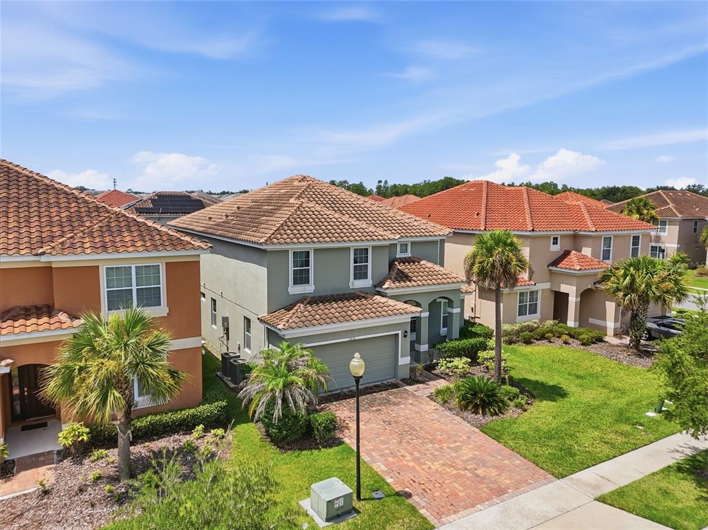 An aerial view shows three two-story houses with tiled roofs and brick driveways — 4416 SHIVA LOOP, KISSIMMEE, FL