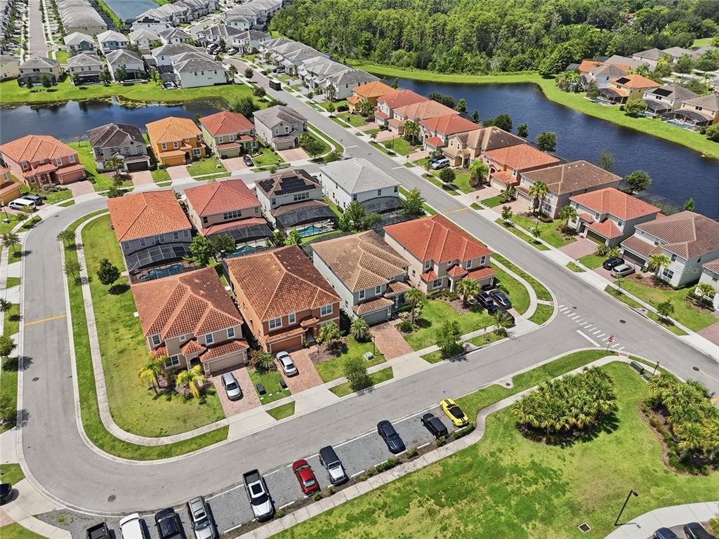 An aerial view shows a suburban neighborhood with houses, a pond, and street parking — 4416 SHIVA LOOP, KISSIMMEE, FL