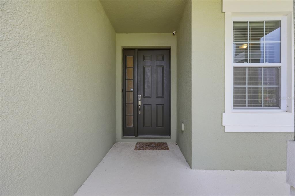 The image shows a covered entryway with a dark front door and a single window — 4416 SHIVA LOOP, KISSIMMEE, FL
