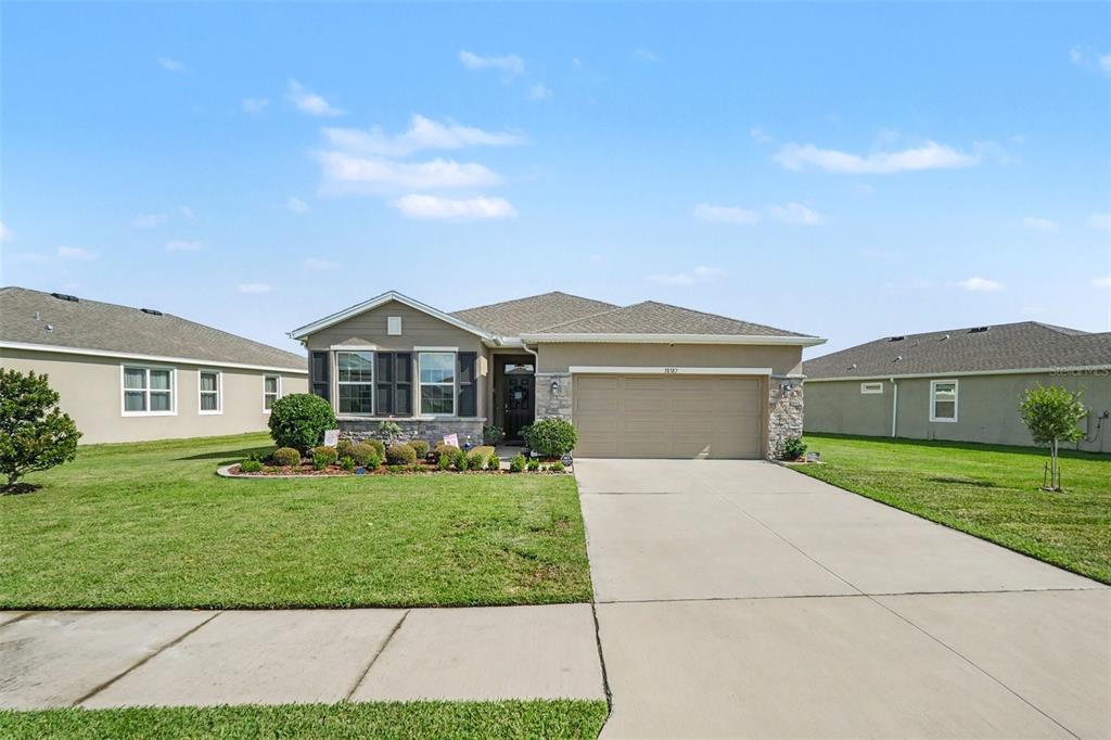 A single-story house with a beige stucco exterior, stone accents, and a two-car garage — 38387 SPRINGHEAD LN, ZEPHYRHILLS, FL