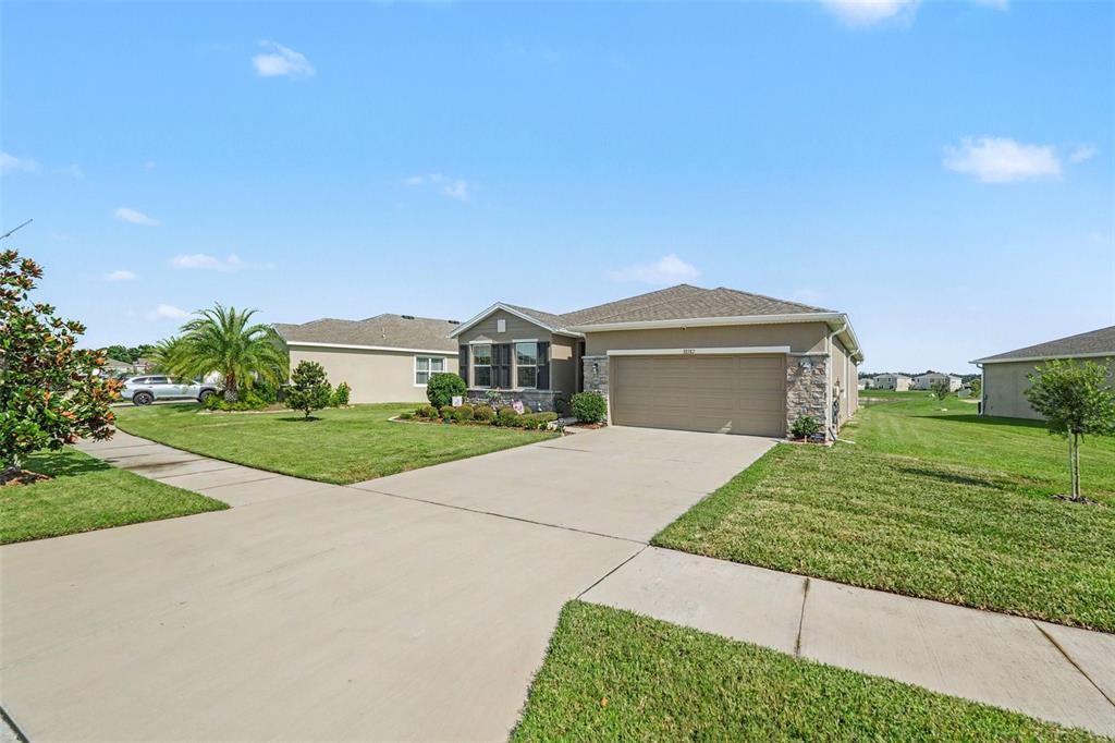 A single-story suburban house with a tan stucco exterior, stone accents, and a two-car garage — 38387 SPRINGHEAD LN, ZEPHYRHILLS, FL