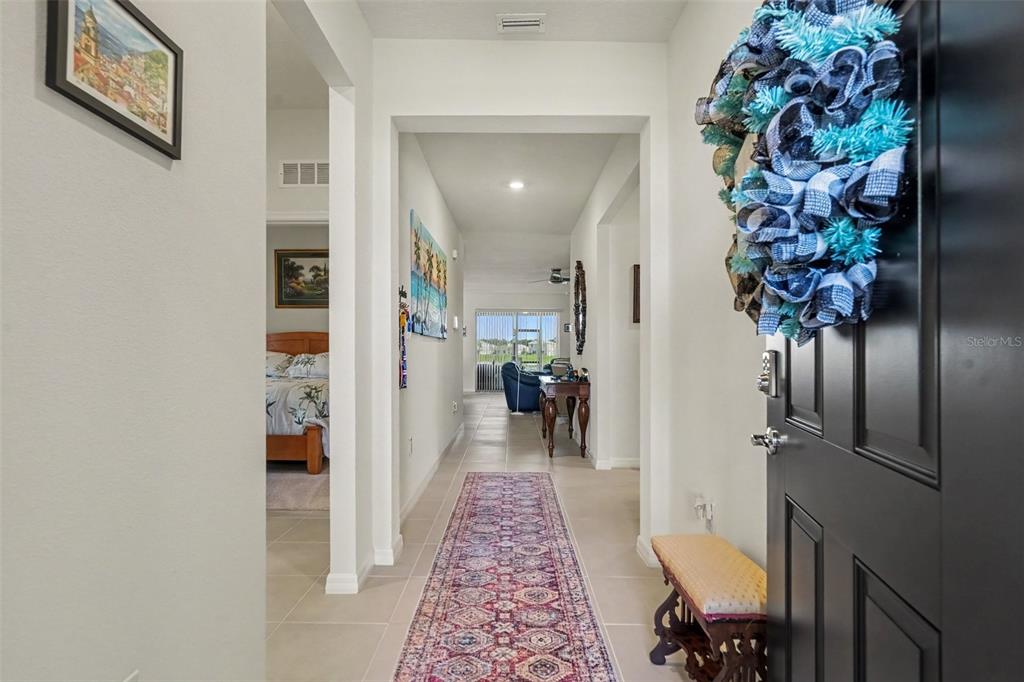 A hallway with tile flooring leads from a front door into a living area — 38387 SPRINGHEAD LN, ZEPHYRHILLS, FL