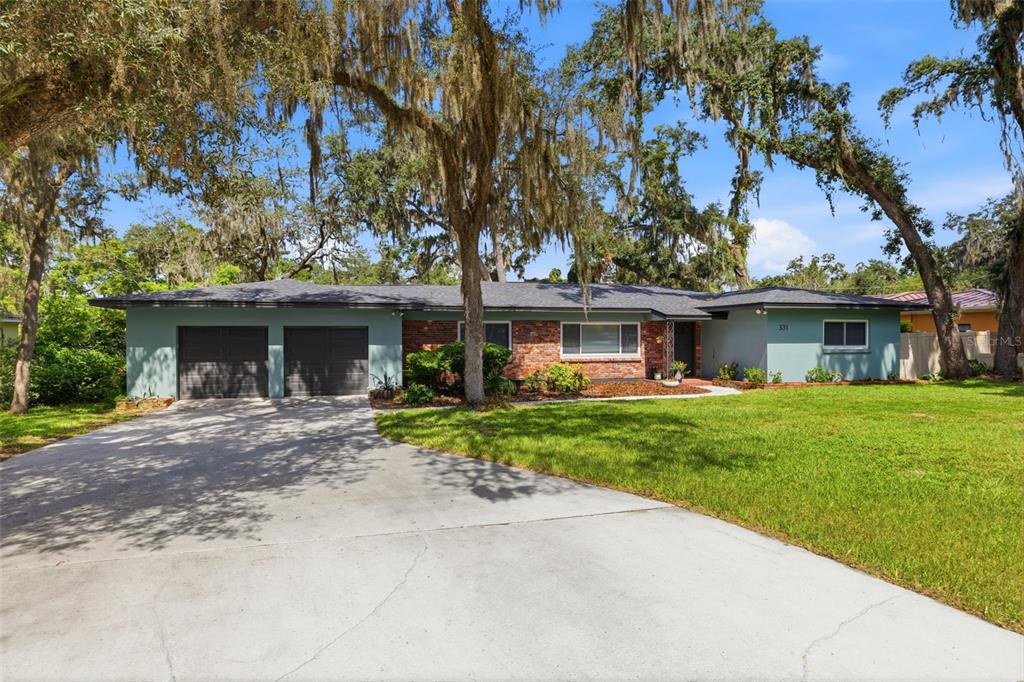 A single-story house with a brick and teal exterior, a two-car garage, and large oak trees — 331 SUNNYSIDE ROAD, TEMPLE TERRACE, FL