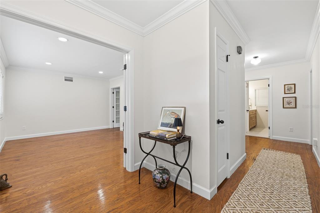 A hallway with hardwood floors leads to an open room and a bathroom doorway — 331 SUNNYSIDE ROAD, TEMPLE TERRACE, FL