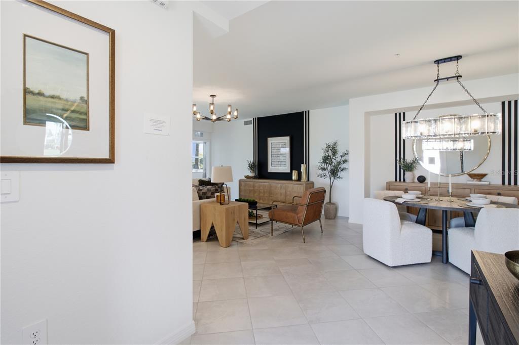 A bright, open-concept living and dining area features light tile flooring and modern light fixtures — 19235 CHERRYSTONE WAY UNIT 104, LAKEWOOD RANCH, FL
