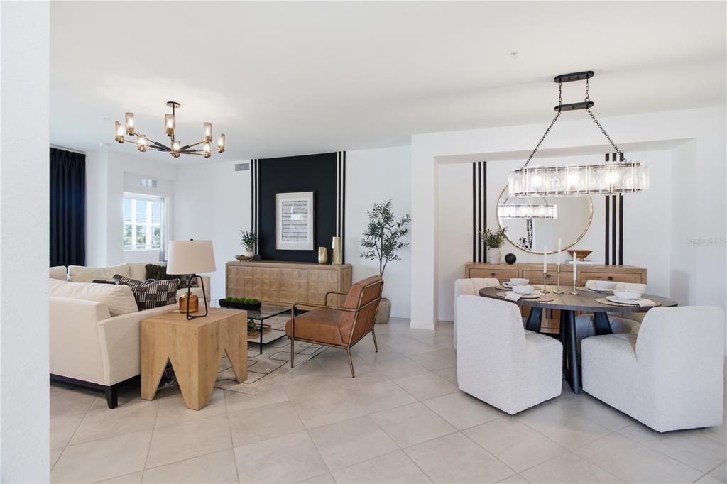 An open-concept living and dining area features modern chandeliers, neutral furniture, and black accent walls — 19235 CHERRYSTONE WAY UNIT 104, LAKEWOOD RANCH, FL