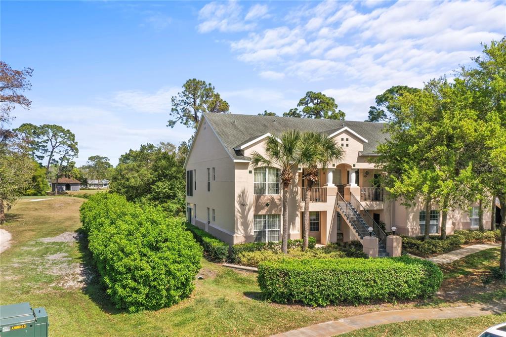 A two-story apartment building with beige stucco walls, a shingled roof, and exterior staircases — 710 AUGUSTA CIRCLE UNIT 11A, ST AUGUSTINE, FL