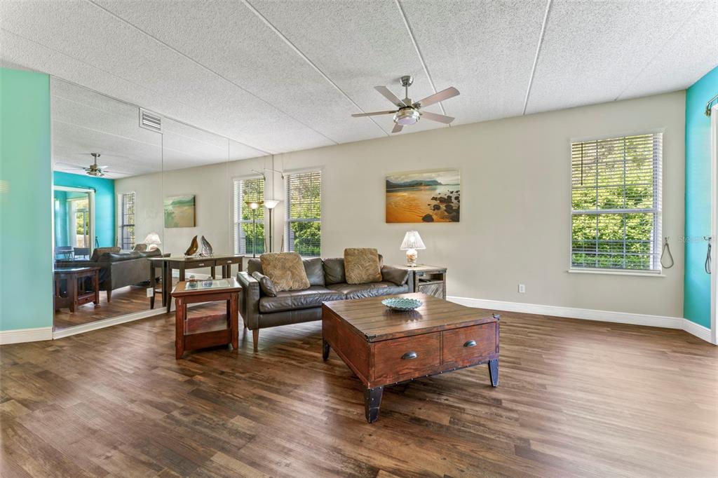 A living room features wood-look flooring, a mirrored wall, a leather sofa, and a coffee table — 710 AUGUSTA CIRCLE UNIT 11A, ST AUGUSTINE, FL