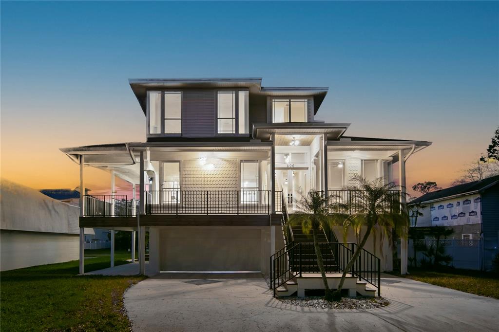 A large multi-story house sits beside a grassy lawn overlooking the ocean at sunset — 606 INDIANA AVENUE, CRYSTAL BEACH, FL
