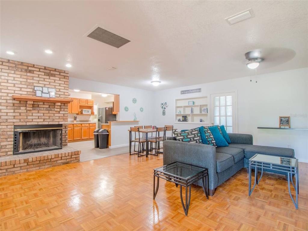 A living room with a brick fireplace, hardwood floors, and an adjacent dining area — 4401 LENMORE STREET, ORLANDO, FL