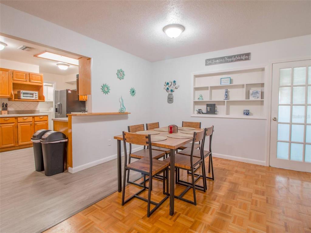 A dining area with a wooden table, four chairs, built-in shelving, and a kitchen pass-through — 4401 LENMORE STREET, ORLANDO, FL