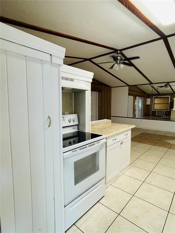 A kitchen features white cabinets, a white stove, and light-colored tile flooring — 1335 S MARTIN LUTHER KING JR AVENUE, CLEARWATER, FL