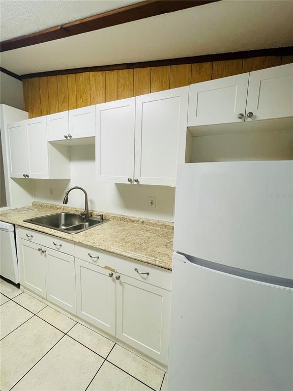 A kitchen features white cabinets, a beige laminate countertop, a stainless steel sink, and tile flooring — 1335 S MARTIN LUTHER KING JR AVENUE, CLEARWATER, FL