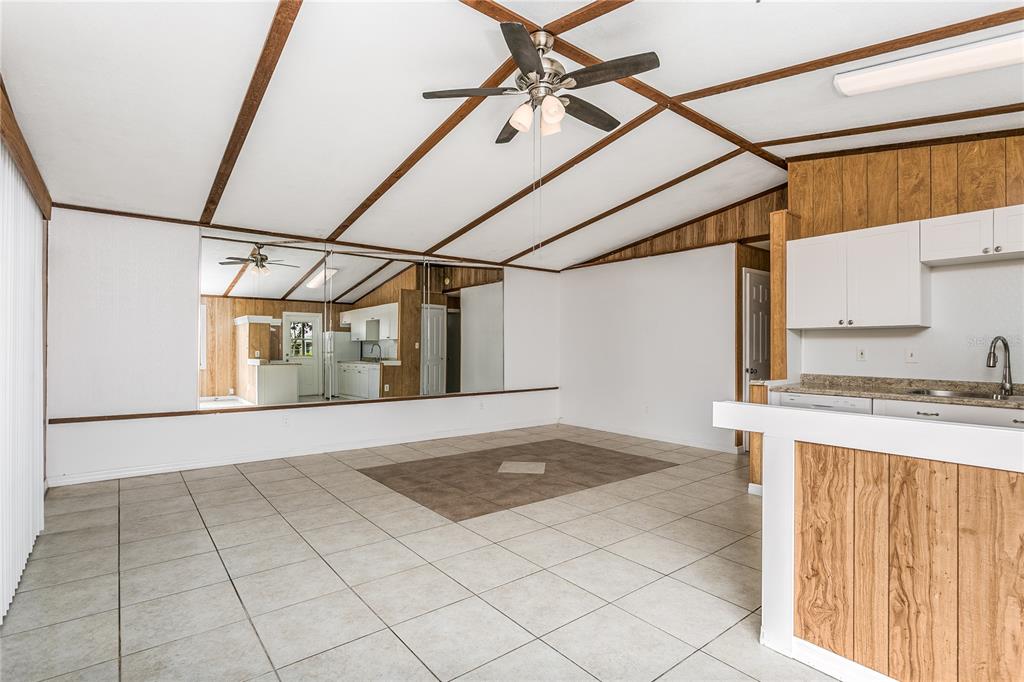 A living room with tiled floors, a mirrored wall, and a wood-paneled kitchen counter — 1335 S MARTIN LUTHER KING JR AVENUE, CLEARWATER, FL