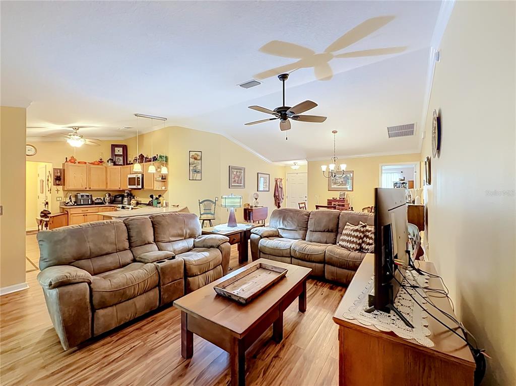 A living room features two brown reclining sofas, a wooden coffee table, and an open kitchen — 1016 MATTHEW AVENUE, LADY LAKE, FL