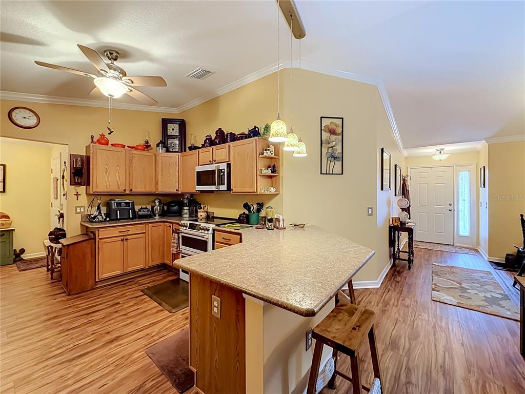A kitchen with wood cabinets, a granite-topped island, and light wood flooring — 1016 MATTHEW AVENUE, LADY LAKE, FL