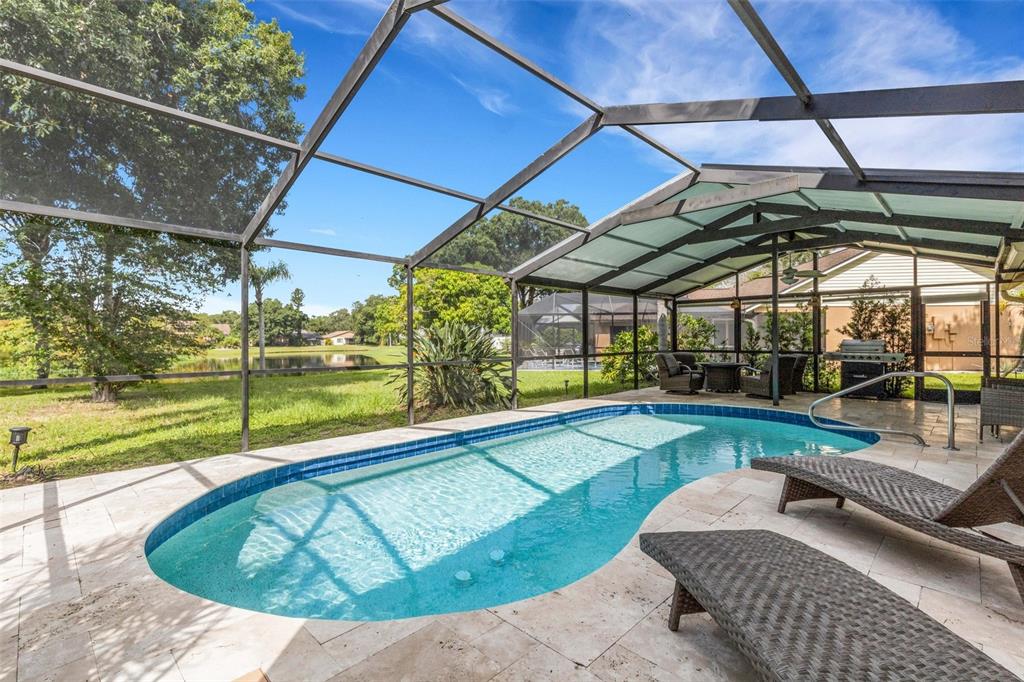 A screened-in patio features a swimming pool, stone pavers, and lounge chairs overlooking a pond — 3476 SHADY BROOK LANE, SARASOTA, FL