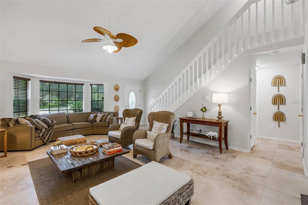 A living room features a vaulted ceiling, a staircase, wicker armchairs, and a sectional sofa — 3476 SHADY BROOK LANE, SARASOTA, FL