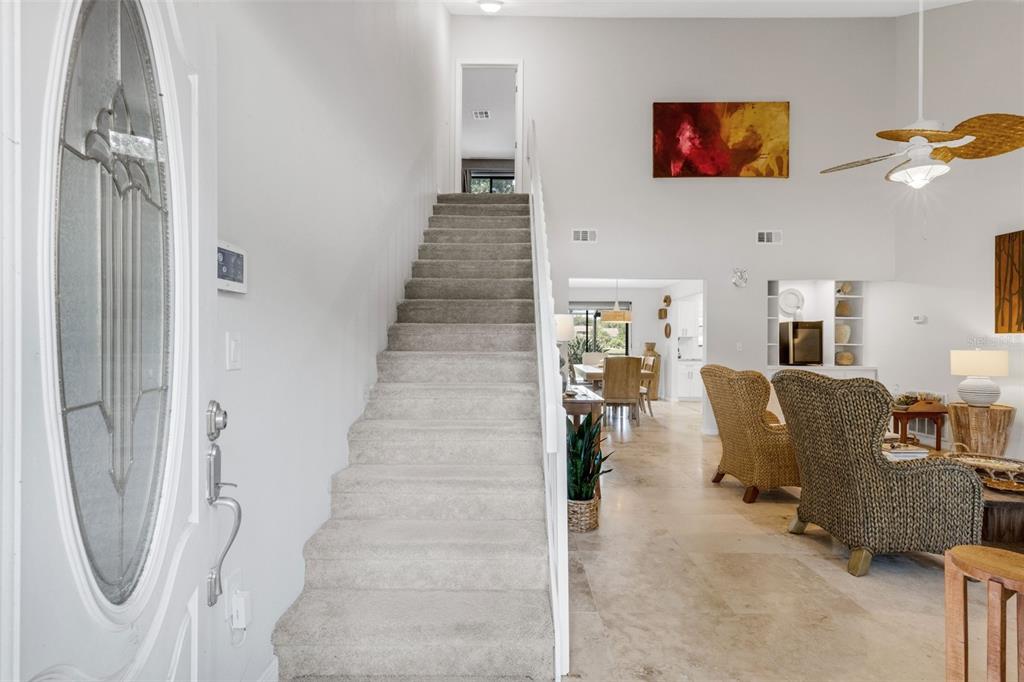 An entryway features a carpeted staircase, a white front door, and a view into the living room — 3476 SHADY BROOK LANE, SARASOTA, FL