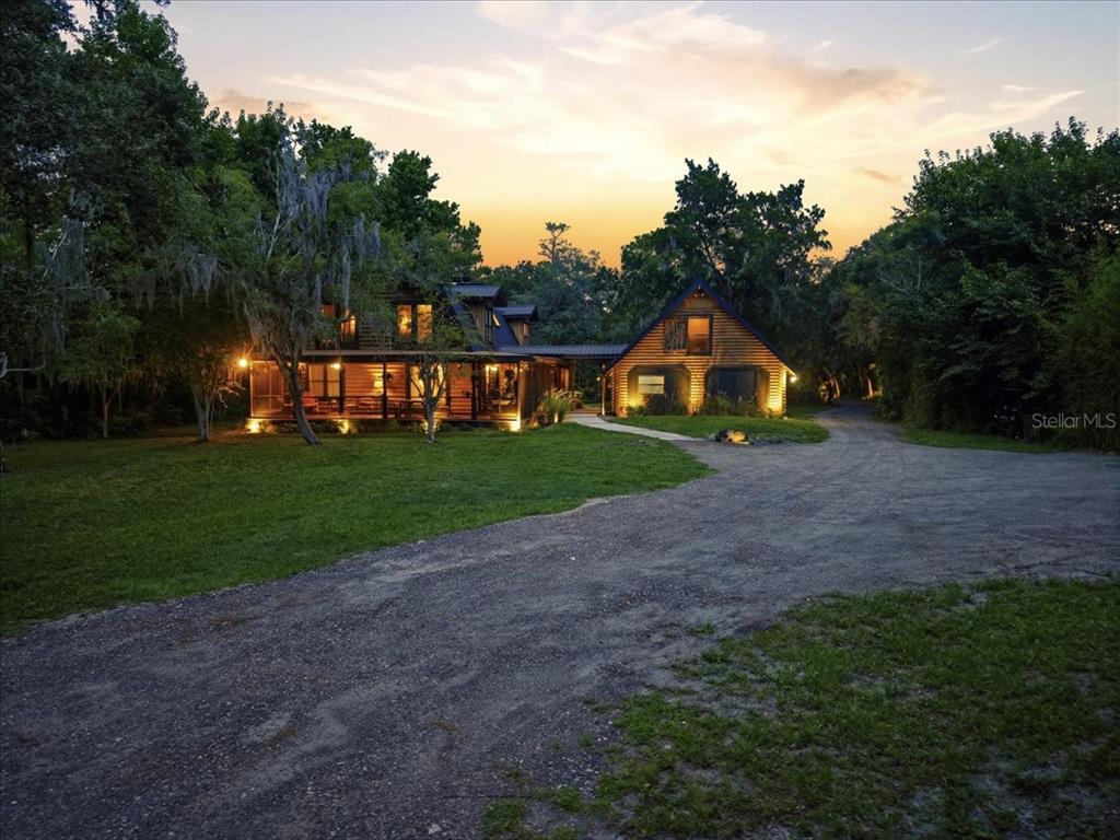A two-story wooden cabin with a large porch and attached garage at sunset — 1630 STILLMEADOW ROAD, DELTONA, FL
