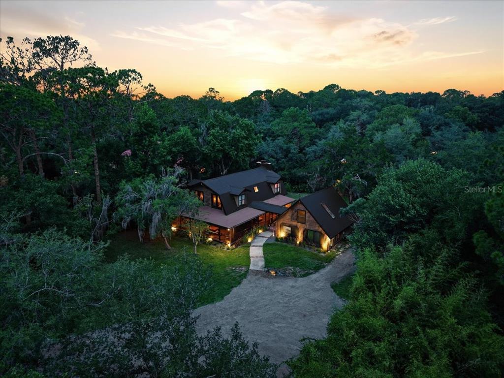 An aerial view of a two-story house with a dark metal roof nestled in trees — 1630 STILLMEADOW ROAD, DELTONA, FL