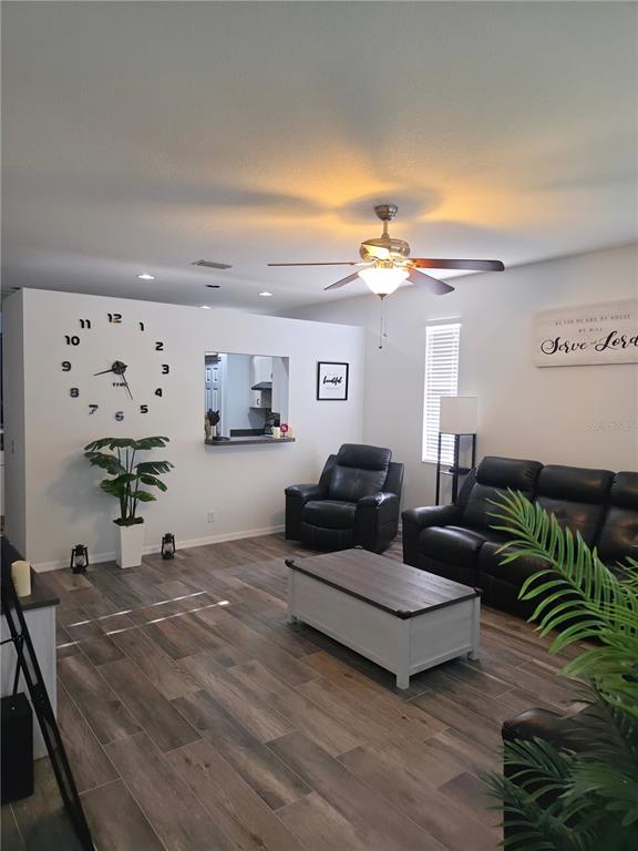 A living area features wood-look tile flooring, a large wall clock, and a potted plant — 3328 70TH COURT E, PALMETTO, FL