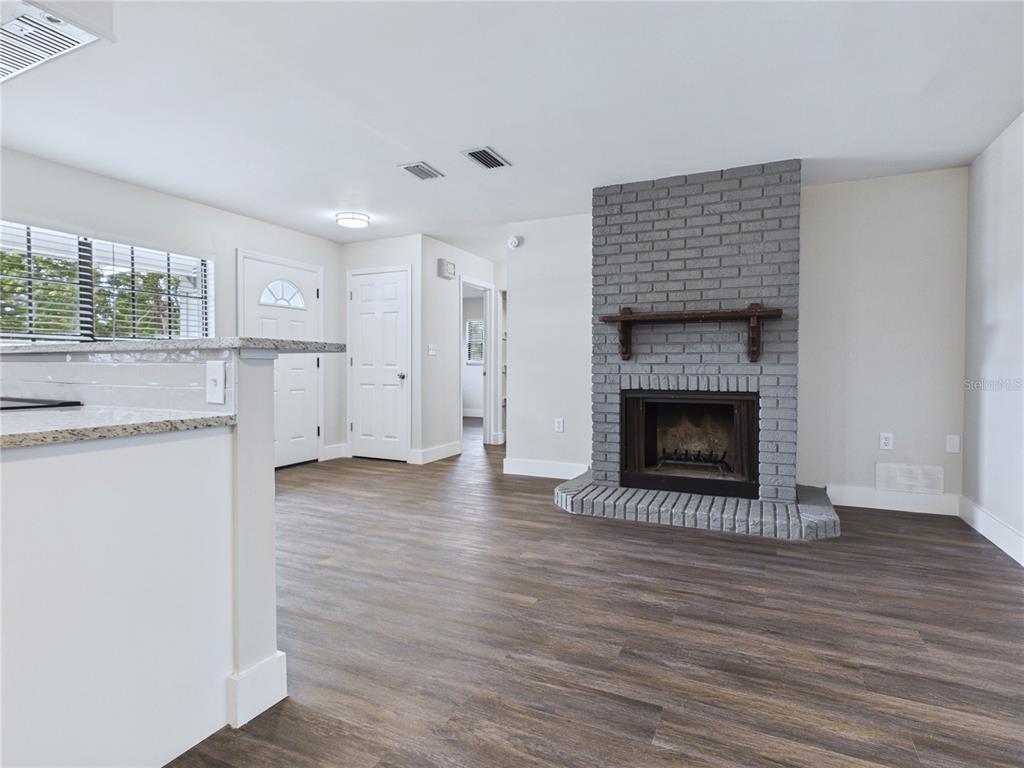 A living room features wood-look flooring, a gray brick fireplace, and an adjacent kitchen counter — 457 WATER ROAD, OCALA, FL