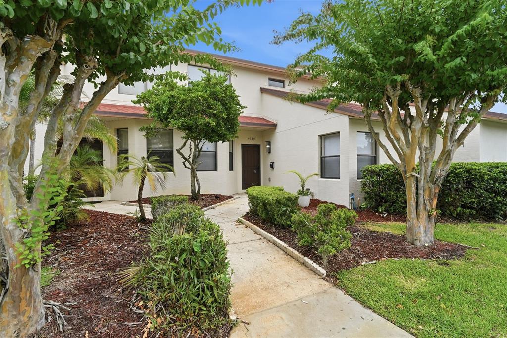 A concrete walkway leads to the front entrance of a two-story beige townhouse — 4125 S LAKE ORLANDO PARKWAY UNIT 4125, ORLANDO, FL