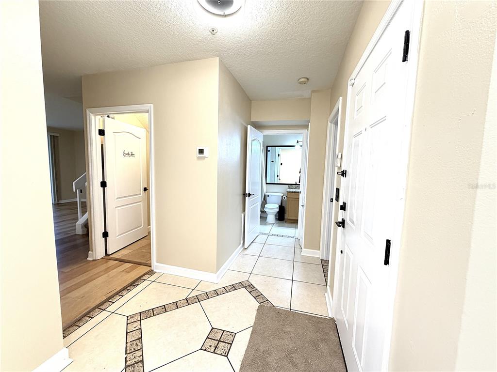 An entryway with tiled flooring leads to a bathroom and a room with wood floors — 4125 S LAKE ORLANDO PARKWAY UNIT 4125, ORLANDO, FL