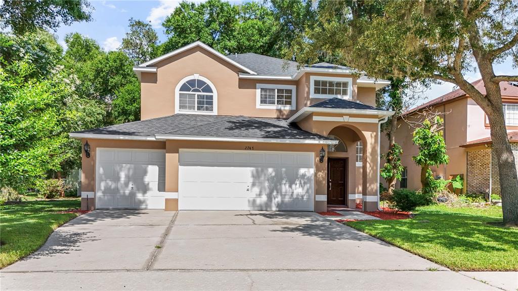 A two-story house with a tan stucco exterior, a three-car garage, and a concrete driveway — 2247 MOUNTAIN SPRUCE STREET, OCOEE, FL