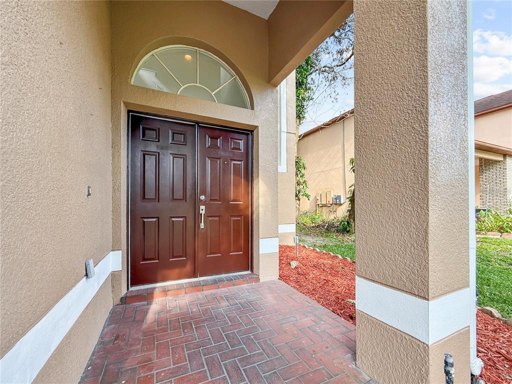 A covered entryway features a brick floor, a brown double door, and an arched transom window — 2247 MOUNTAIN SPRUCE STREET, OCOEE, FL