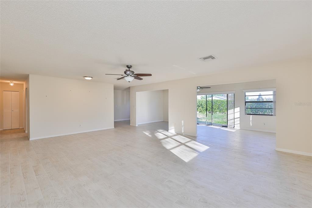 A spacious, light-filled living room features neutral walls, light-colored tile flooring, and a ceiling fan — 2321 LANCASTER DRIVE, SUN CITY CENTER, FL