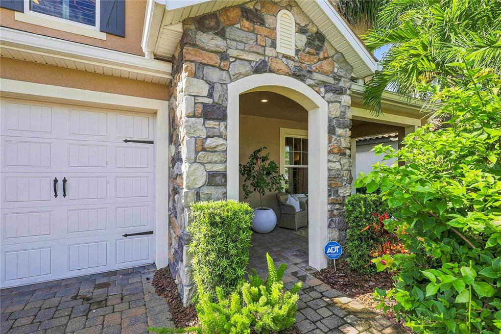 A stone-accented entryway with a white garage door and a small patio area — 12320 TERRACOTTA DRIVE, BRADENTON, FL