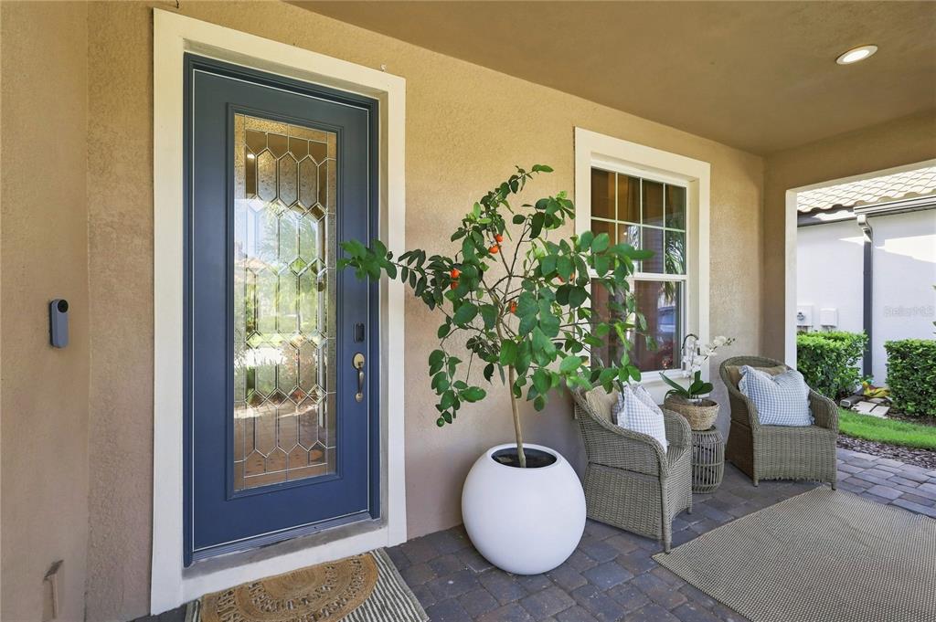A covered front porch features a blue door with glass inlay, two wicker chairs, and a plant — 12320 TERRACOTTA DRIVE, BRADENTON, FL