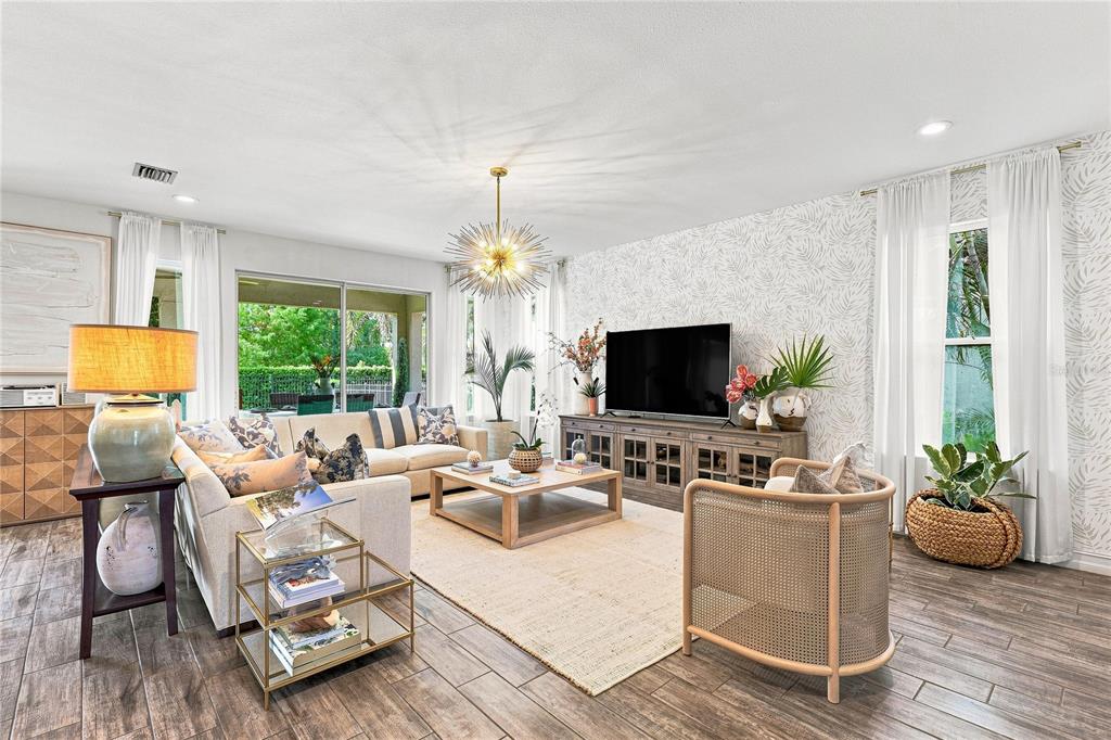 A living room features a patterned accent wall, a large chandelier, and neutral-toned furniture — 12320 TERRACOTTA DRIVE, BRADENTON, FL
