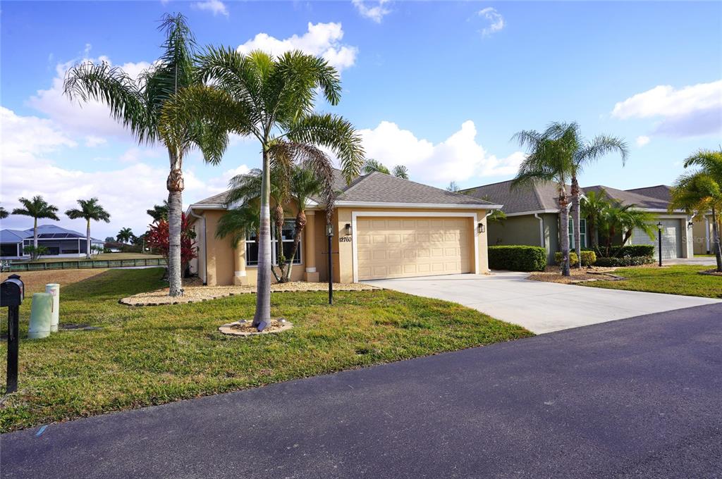 A tan single-story house with a two-car garage and palm trees in the front yard — 12760 SW LAKE SIDE DRIVE, ARCADIA, FL